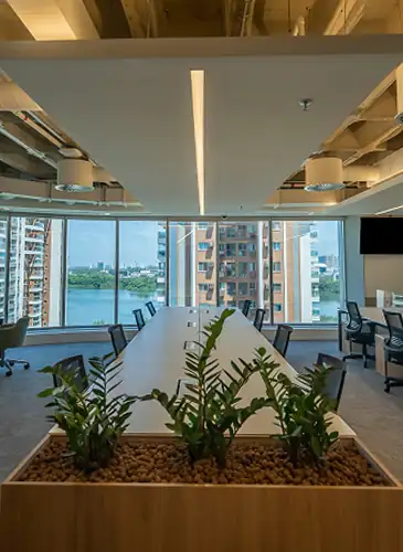 Área colaborativa de escritório corporativo da Huawei com mesa ampla, cadeiras ergonômicas e jardim interno, destacando obra corporativa realizada pela Custódio.