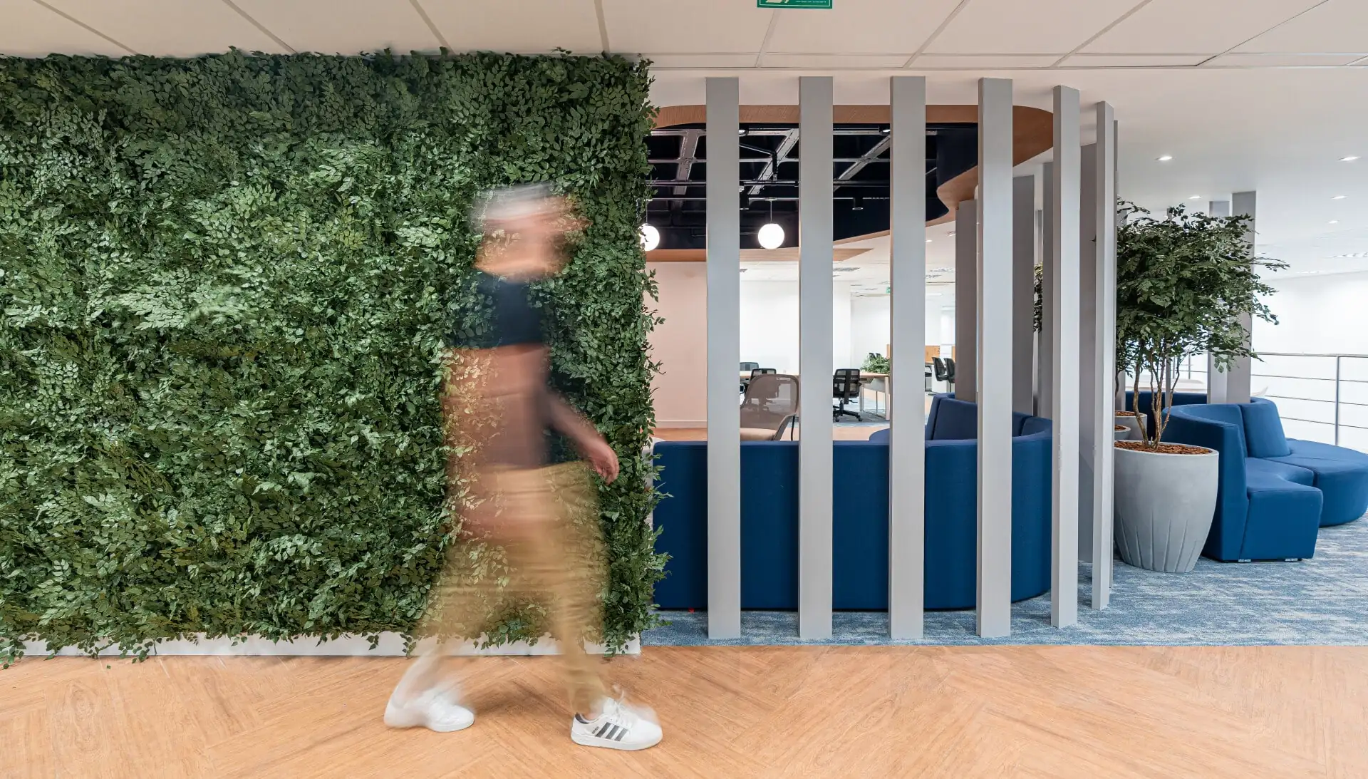 Parede verde integrada a divisórias metálicas em área corporativa moderna, destacando projeto de arquitetura e reforma de escritório realizados pela Custódio.