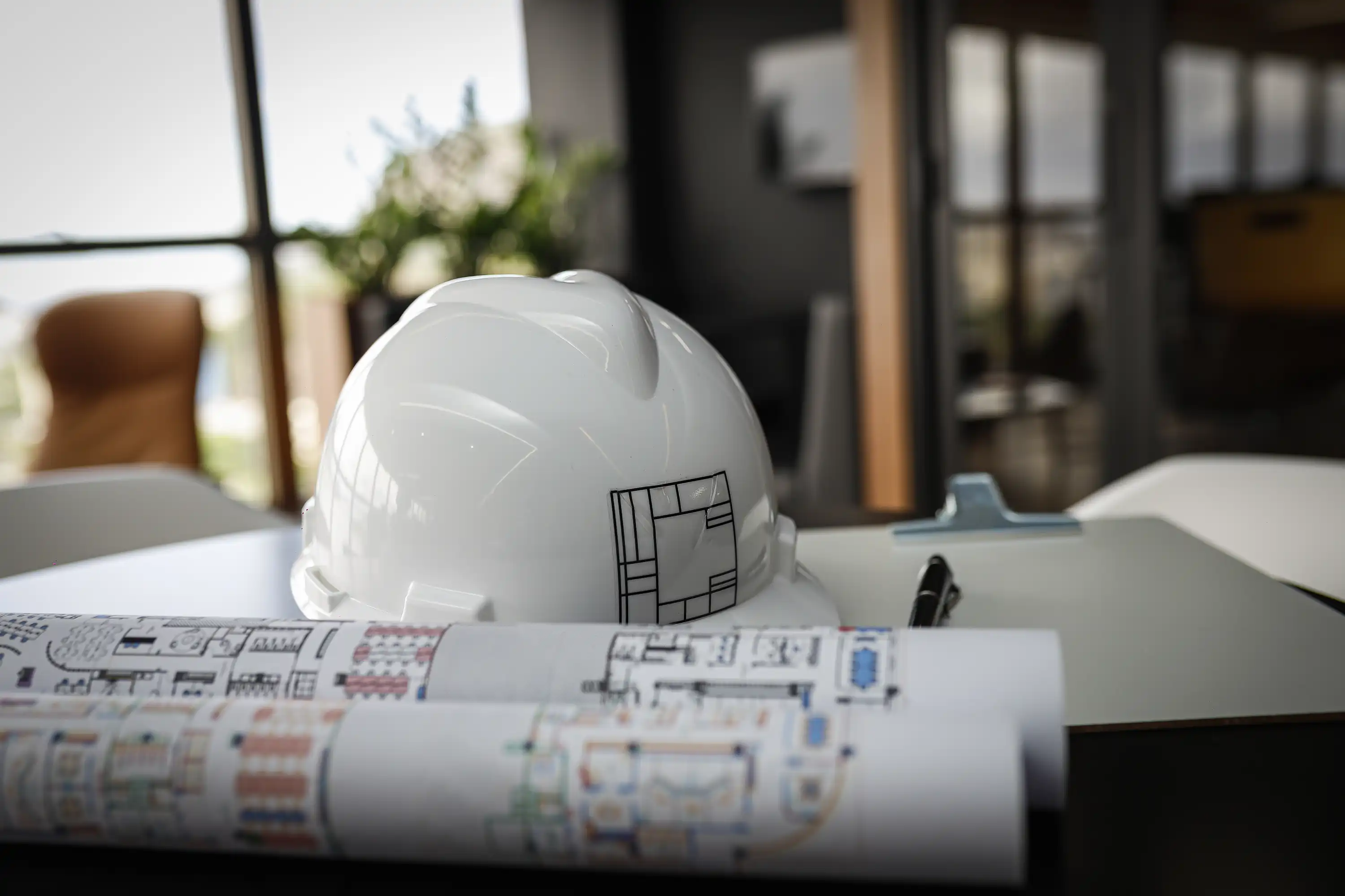 Capacete da Custódio sobre mesa com plantas arquitetônicas, representando o planejamento e a execução de obras corporativas. Imagem institucional que simboliza excelência em projetos de arquitetura e reformas de escritórios.