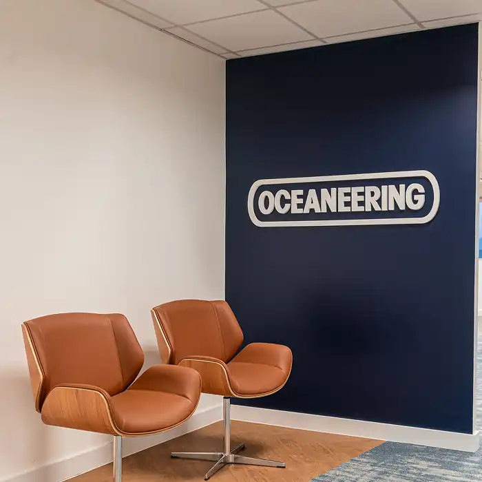 Lounge do escritório corporativo da Oceaneering, desenvolvido pela Custódio, escritório de arquitetura especializado em obras corporativas e reformas de escritório que unem design, conforto e identidade da marca.