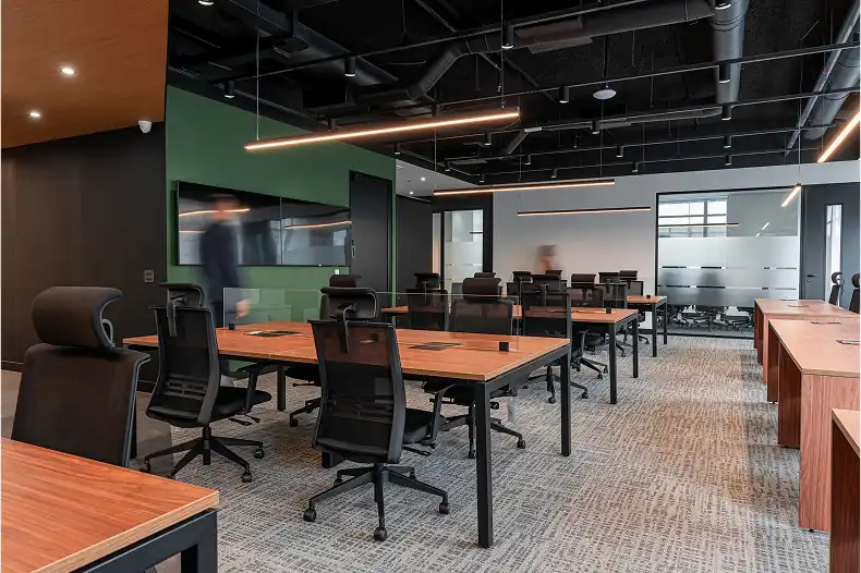 Área de staff do escritório da Oplium em São Paulo, com projeto de arquitetura e execução da obra corporativa pela Custódio. Espaço corporativo moderno, com iluminação linear, teto aparente e mobiliário funcional que valoriza o conforto e a produtividade.