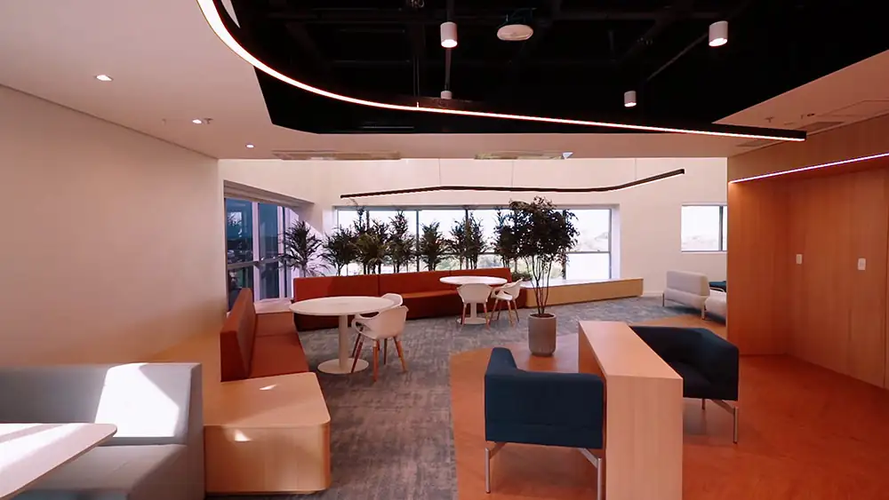 Área de descompressão da Oceaneering no Rio de Janeiro, projetada pela Custódio. Espaço de arquitetura corporativa que combina mobiliário confortável, vegetação integrada e layout acolhedor para promover bem-estar e colaboração.