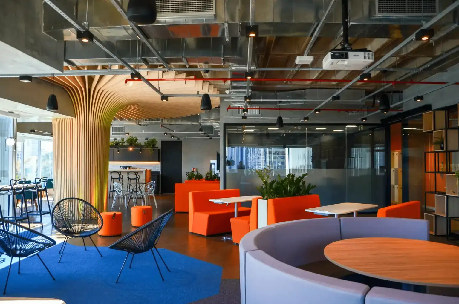 Área de convivência do escritório da EDF com booths laranja, coluna escultural em madeira e mobiliário contemporâneo, criada em projeto de arquitetura desenvolvido por escritório de arquitetura para uma obra corporativa moderna.