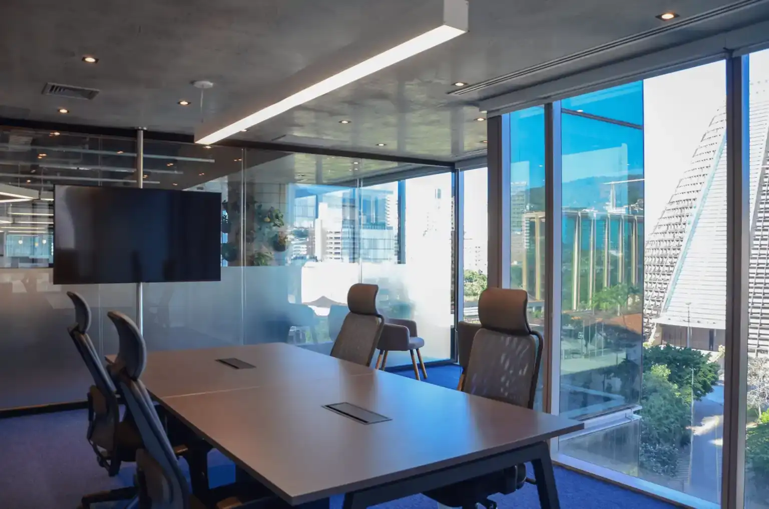Sala de reunião da EDF com mesa executiva, cadeiras ergonômicas e paredes de vidro com vista urbana, destacando projeto de arquitetura desenvolvido por escritório de arquitetura em uma obra corporativa moderna.