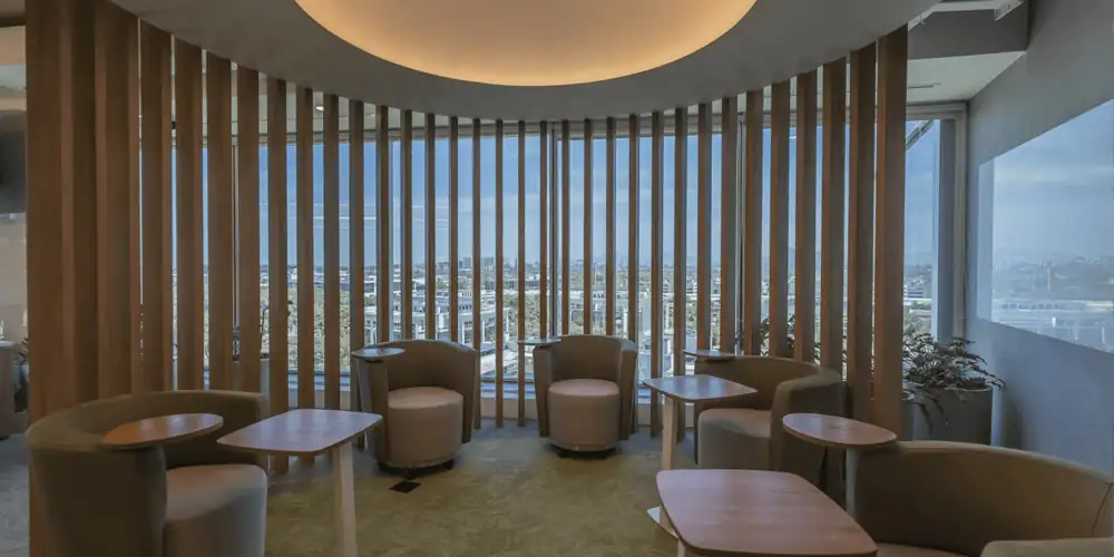 Área de descanso da Huawei com poltronas, mesas individuais e brises de madeira, valorizada pela vista externa, compondo um ambiente criado dentro de um projeto de arquitetura alinhado à obra corporativa e à reforma de escritório realizada pelo escritório de arquitetura.