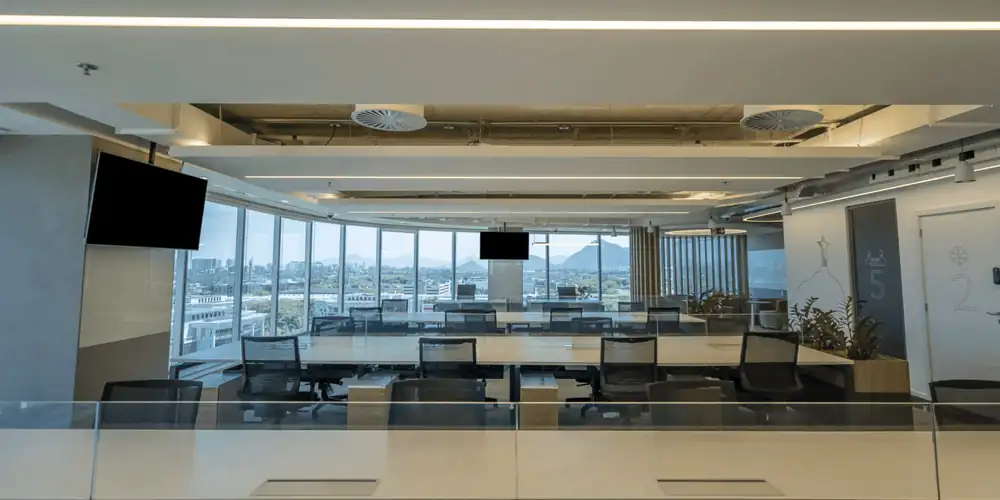 Área de staff da Huawei com estações de trabalho alinhadas, cadeiras corporativas e vista panorâmica, resultado de uma obra corporativa executada com excelência e integrada a um projeto de arquitetura desenvolvido por escritório de arquitetura especializado em reforma corporativa.