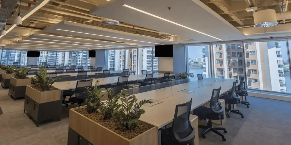 Open space do escritório da Huawei com estações compartilhadas, cadeiras ergonômicas e jardineiras internas, parte de um projeto de arquitetura moderno executado em obra corporativa e integrado a uma reforma de escritório ampla e iluminada.