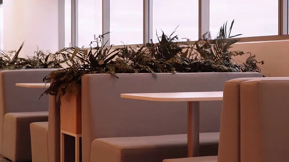 Mesas colaborativas do escritório da Oceaneering no Rio de Janeiro, desenvolvidas pela Custódio. Projeto de arquitetura corporativa que integra vegetação, conforto e funcionalidade para melhorar a experiência no ambiente de trabalho.