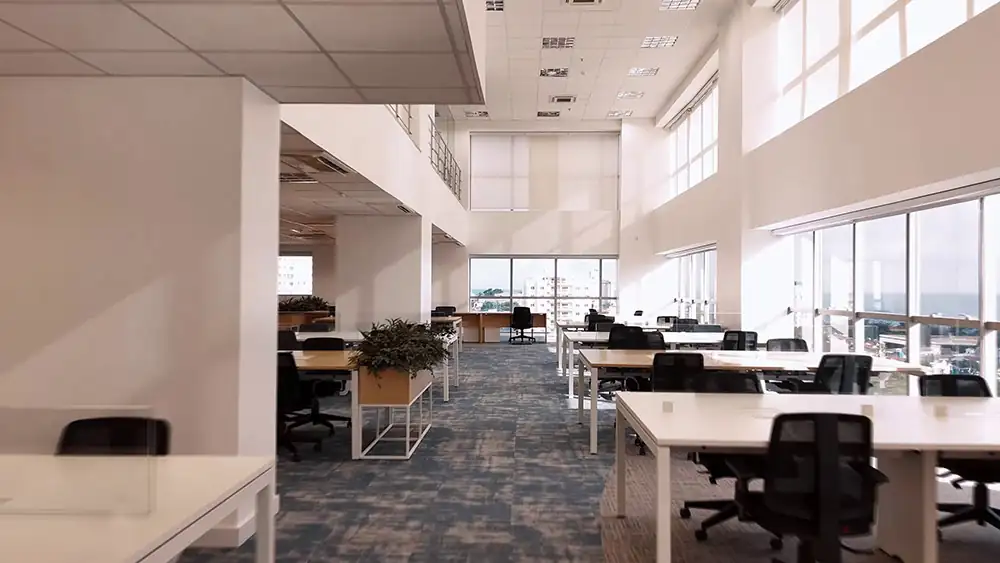 Área ampla de staff da Oceaneering no Rio de Janeiro, projetada pela Custódio. Reforma de escritório corporativo com pé-direito duplo, iluminação natural, estações de trabalho organizadas e layout funcional que reforça produtividade e bem-estar.