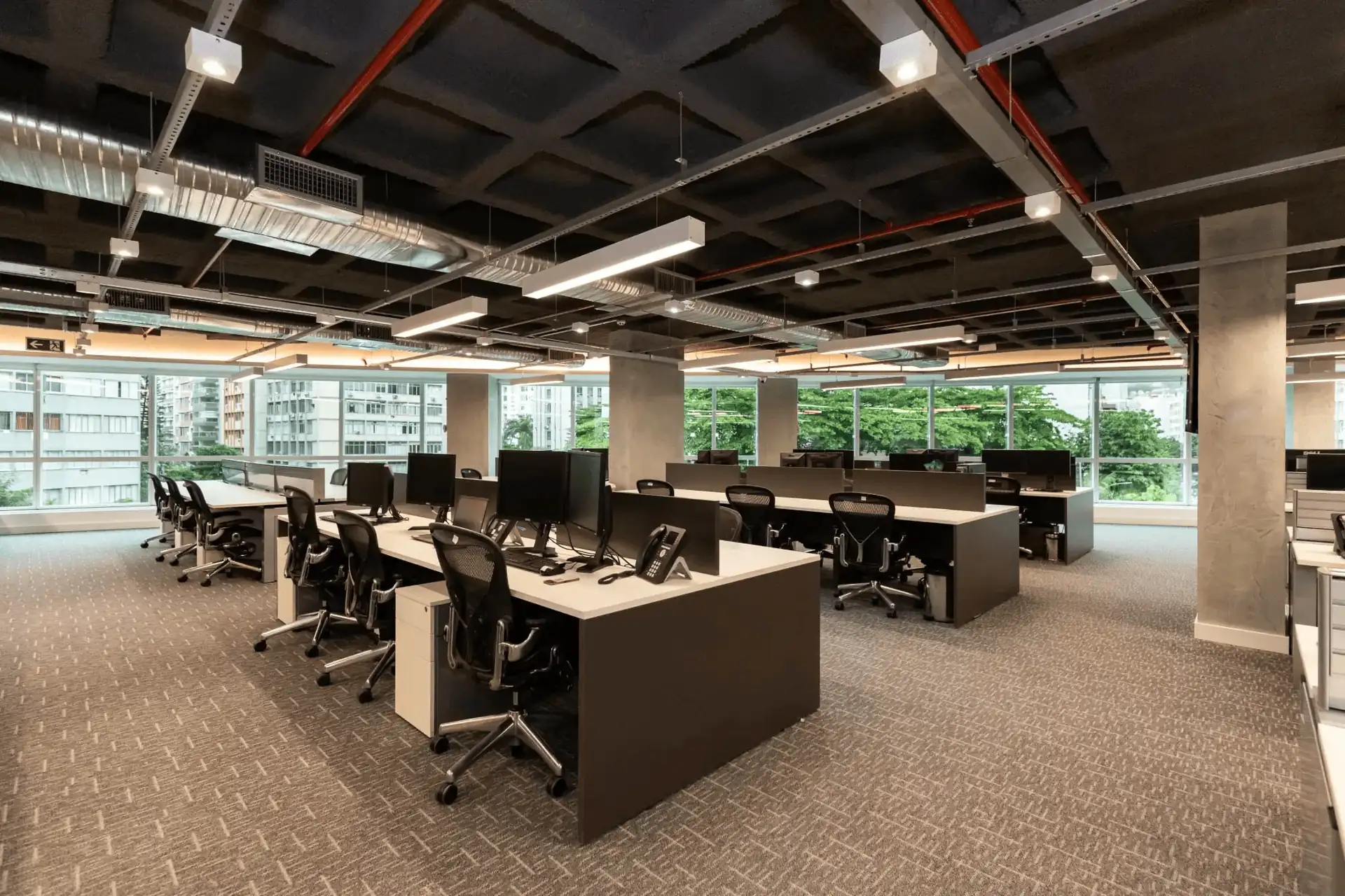 Open space da ATG com estações de trabalho modernas, iluminação industrial e amplas janelas, mostrando como o projeto de arquitetura, a obra corporativa e a reforma de escritório criam um ambiente funcional e bem planejado.