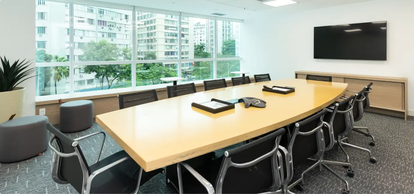 Sala de reunião da ATG com mesa ampla em madeira, cadeiras ergonômicas e vista para a cidade, destacando projeto de arquitetura corporativa, obra corporativa finalizada e reforma de escritório funcional e moderna.