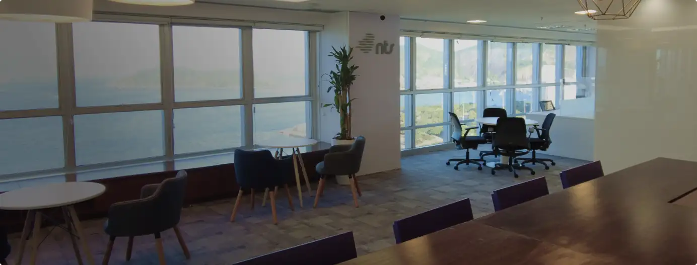 Área informal do escritório da NTS no Rio de Janeiro, desenvolvida pela Custódio. Projeto de arquitetura e obra corporativa que valoriza a vista para o mar e promove conforto, integração e bem-estar aos colaboradores.