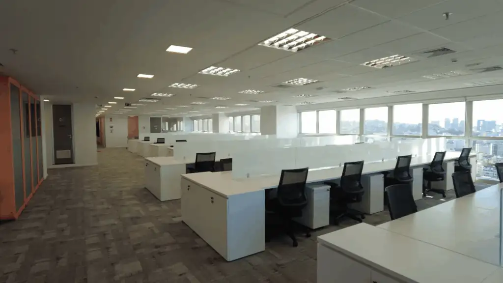 Open space moderno no escritório da NTS, com estações de trabalho alinhadas, cadeiras ergonômicas e iluminação natural abundante. Ambiente projetado por escritório de arquitetura, evidenciando um projeto de arquitetura funcional, obra corporativa completa e reforma de escritório que privilegia conforto, produtividade e layout eficiente.