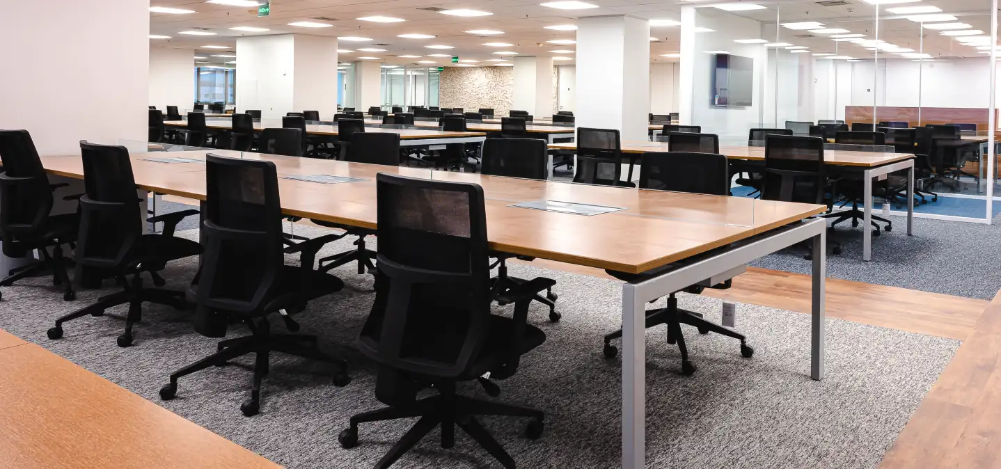 Área operacional do escritório do Parque Bondinho com estações de trabalho amplas, mesas de madeira e cadeiras pretas, resultado de projeto de arquitetura com foco em obra corporativa e reforma de escritório eficiente.