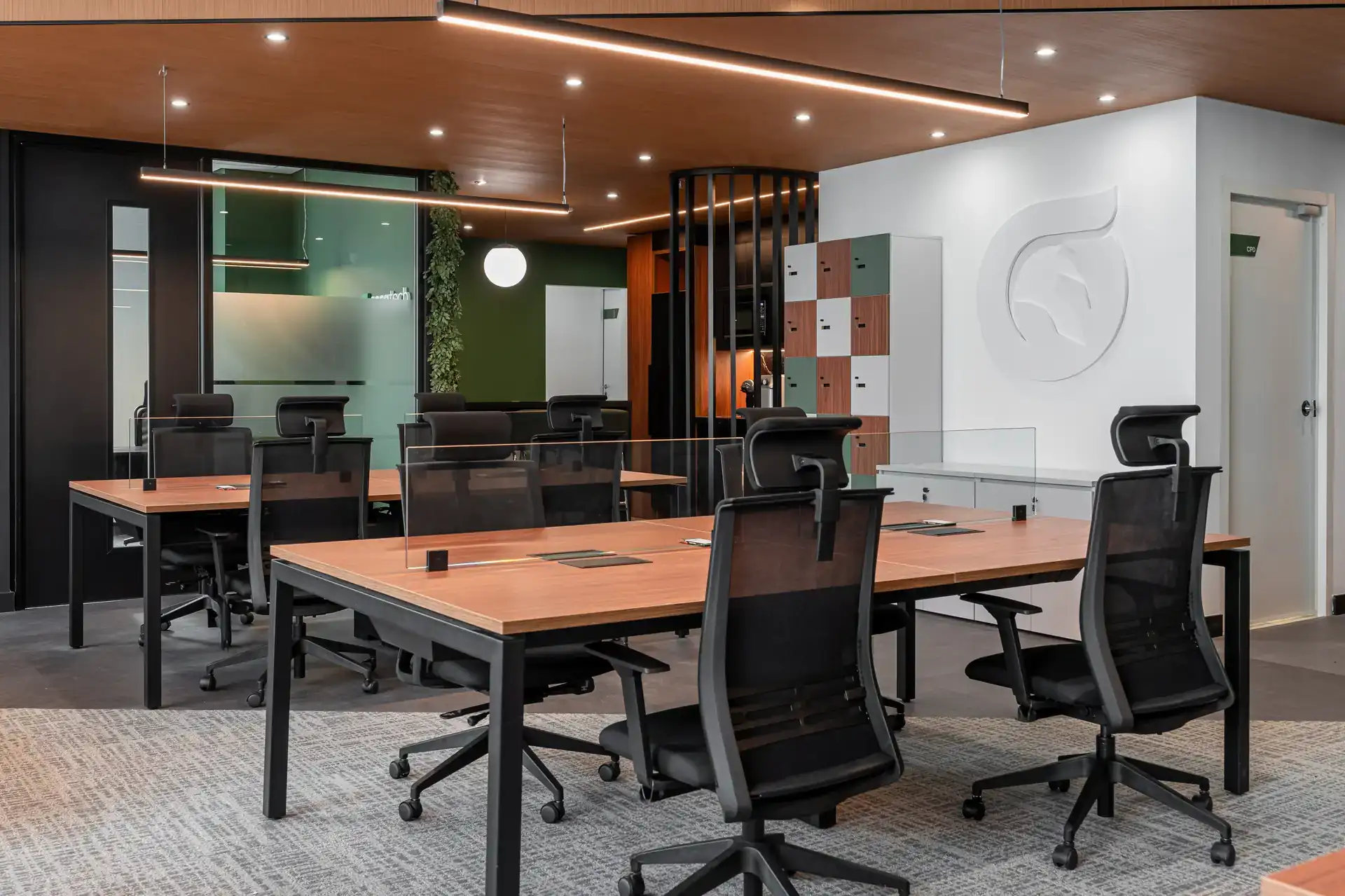 Área operacional do escritório da Oplium com mesas modulares, cadeiras ergonômicas e divisórias de vidro, destacando a eficiência de um projeto de arquitetura corporativa bem planejado.