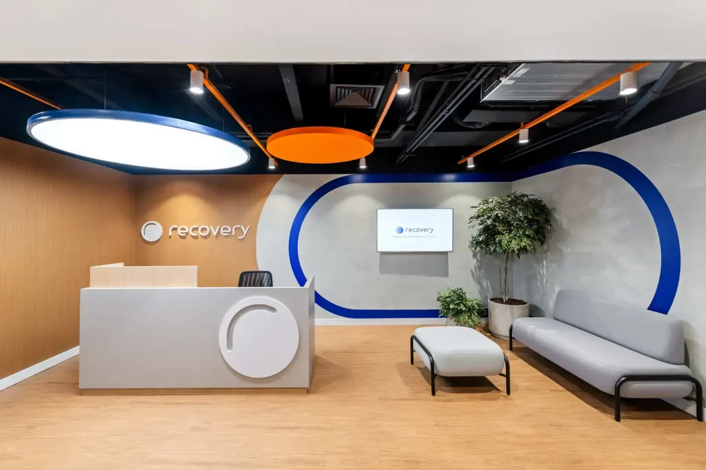 Recepção projetada por escritório de arquitetura com balcão minimalista, luz circular e identidade visual da marca integrada à obra e reforma corporativa.