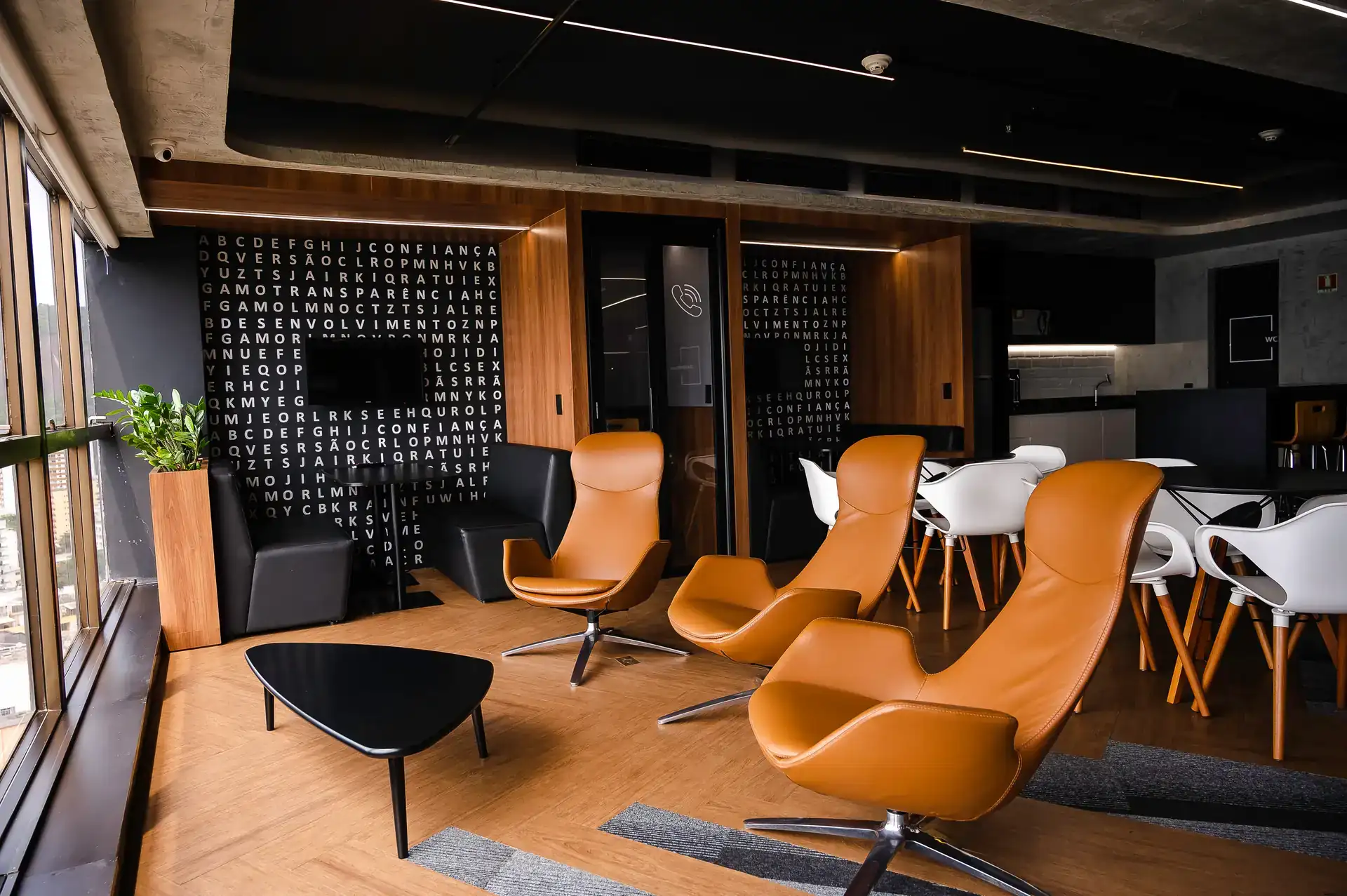 Lounge corporativo com poltronas em couro e painel com tipografia, exemplo de projeto de arquitetura desenvolvido pelo escritório de arquitetura Custódio para reforma corporativa.