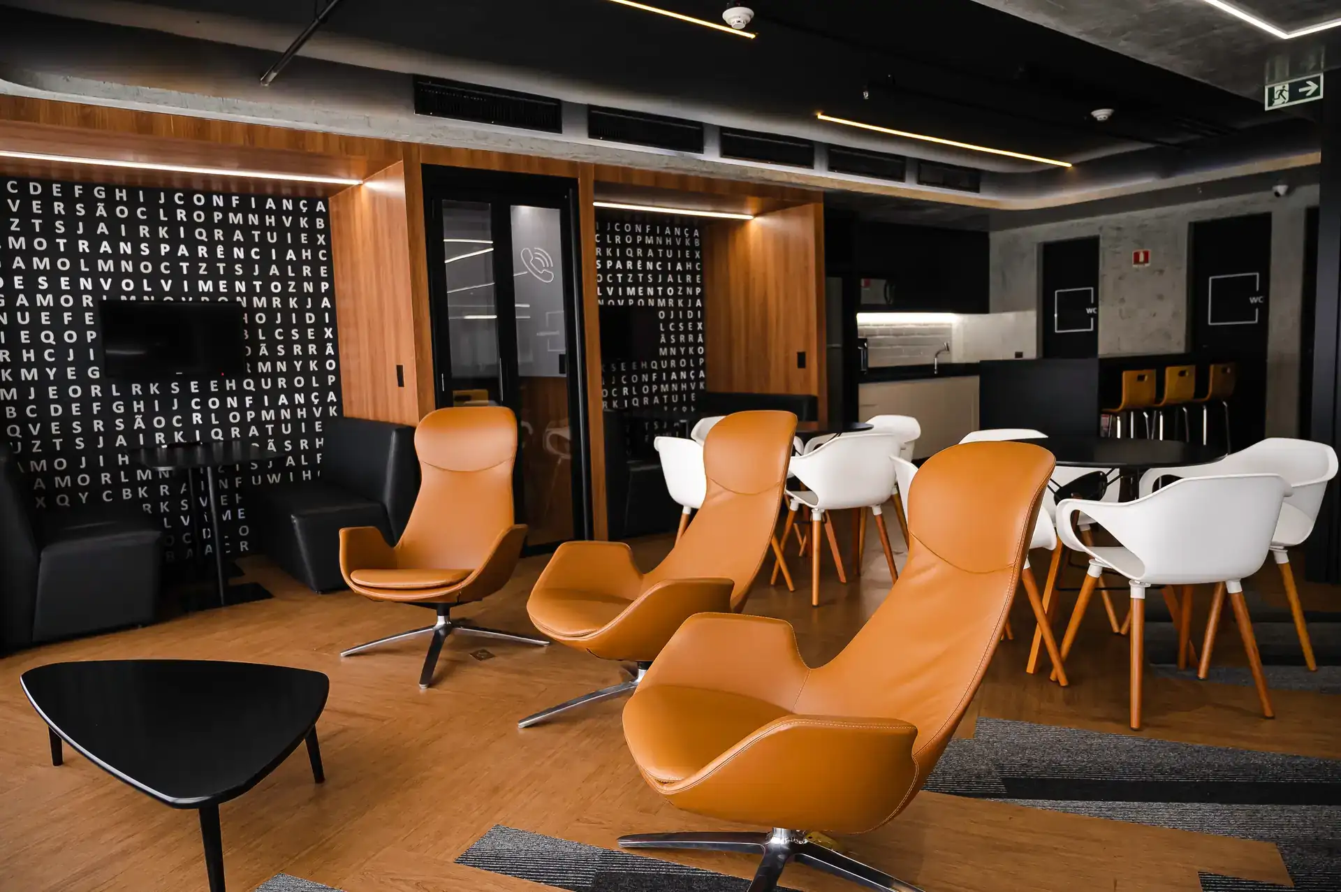 Lounge elegante com poltronas modernas e área de café, resultado de reforma corporativa assinada pelo escritório de arquitetura Custódio no Rio de Janeiro.