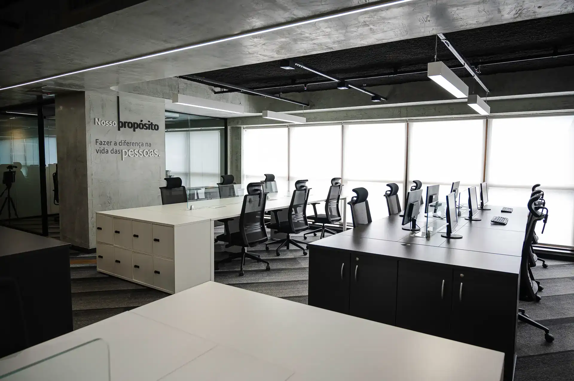 Área aberta de trabalho com mensagem institucional na parede, mostrando o resultado de reforma de escritório em obra corporativa desenvolvida pelo escritório de arquitetura Custódio.