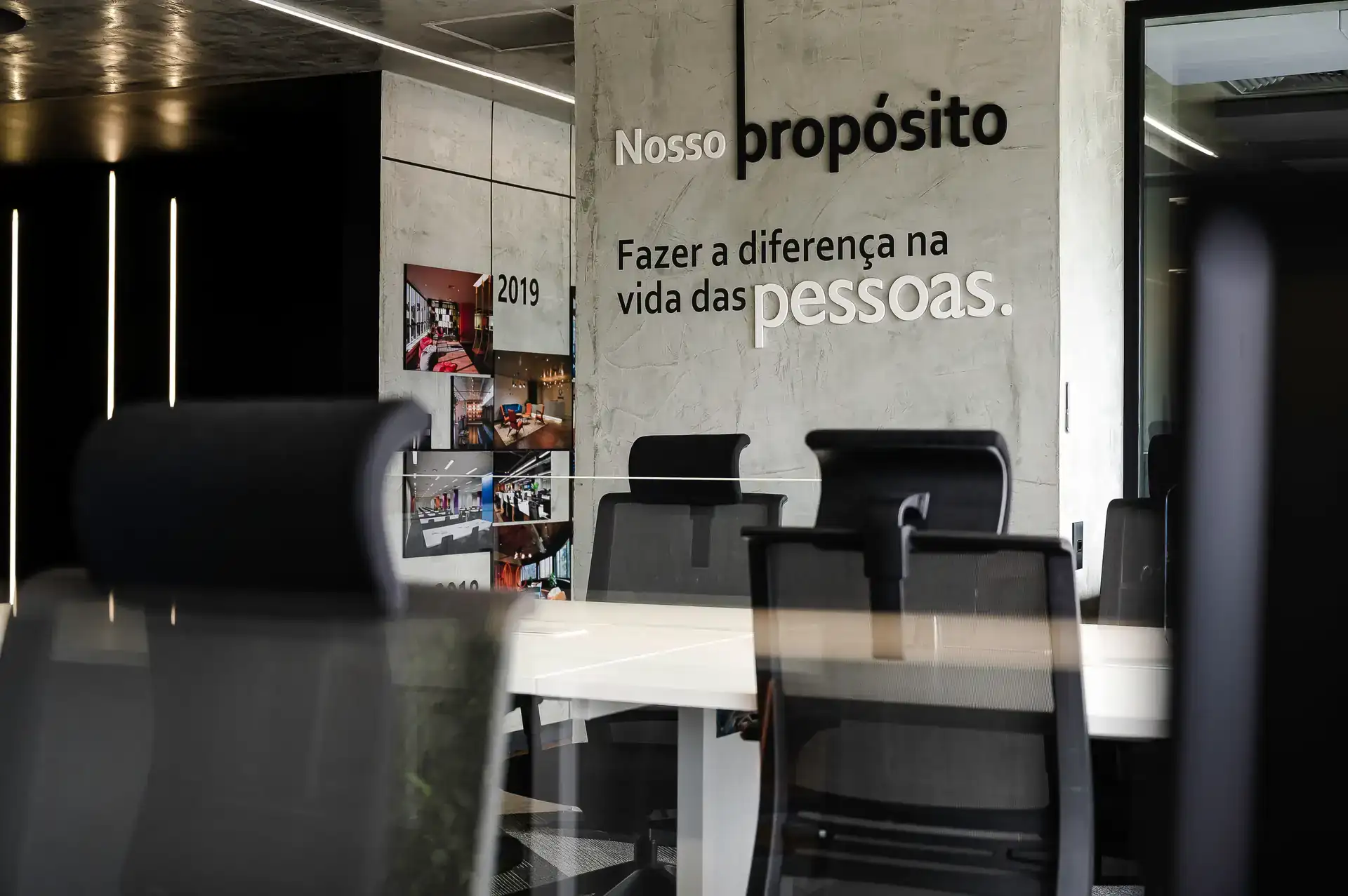 Painel institucional com linha do tempo e frase de propósito, parte de reforma corporativa realizada pelo escritório de arquitetura Custódio no Rio de Janeiro.