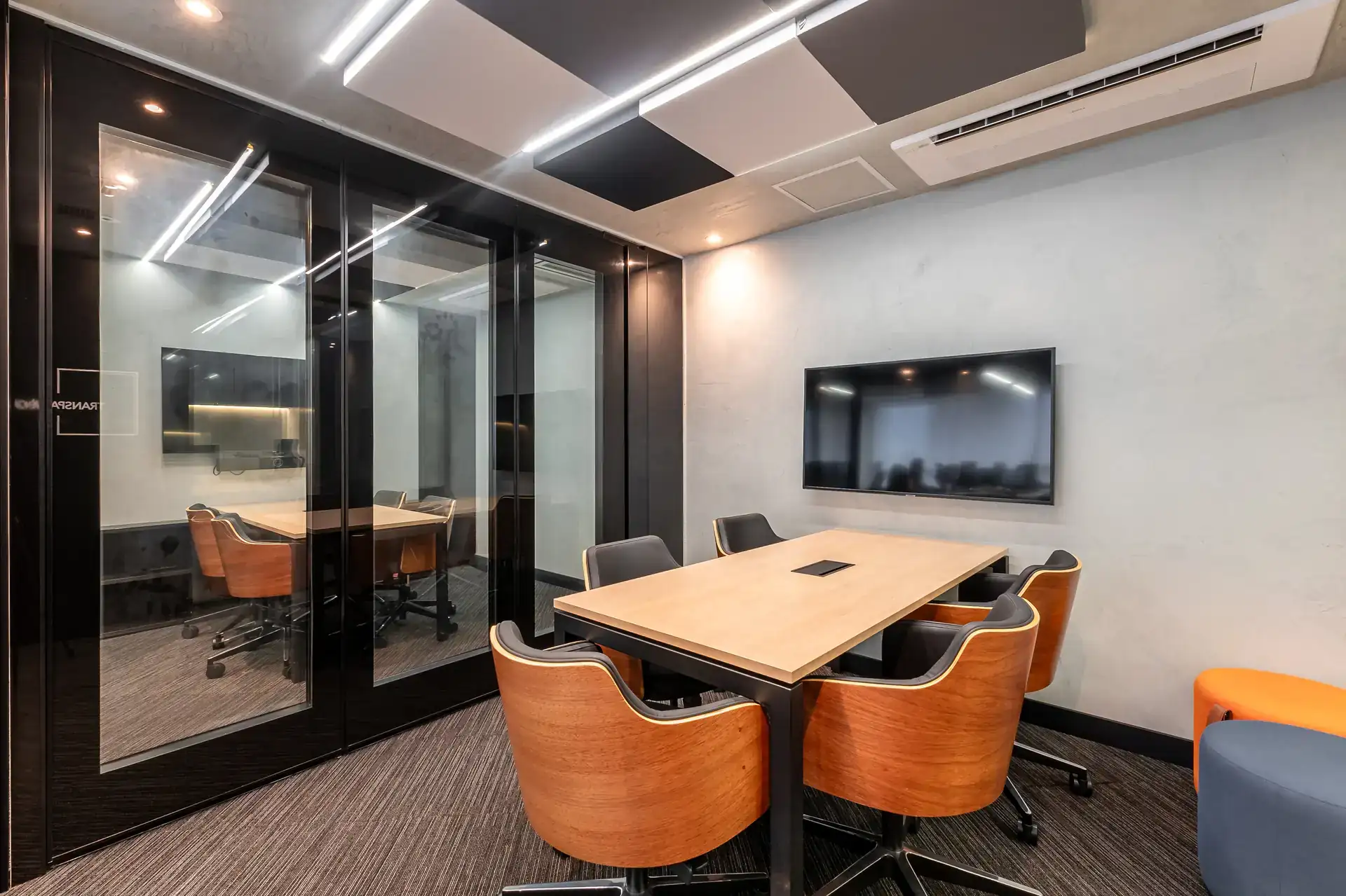 Sala de reunião compacta com mesa madeira, cadeiras ergonômicas e iluminação técnica, evidenciando projeto de arquitetura para escritórios funcional e contemporâneo.