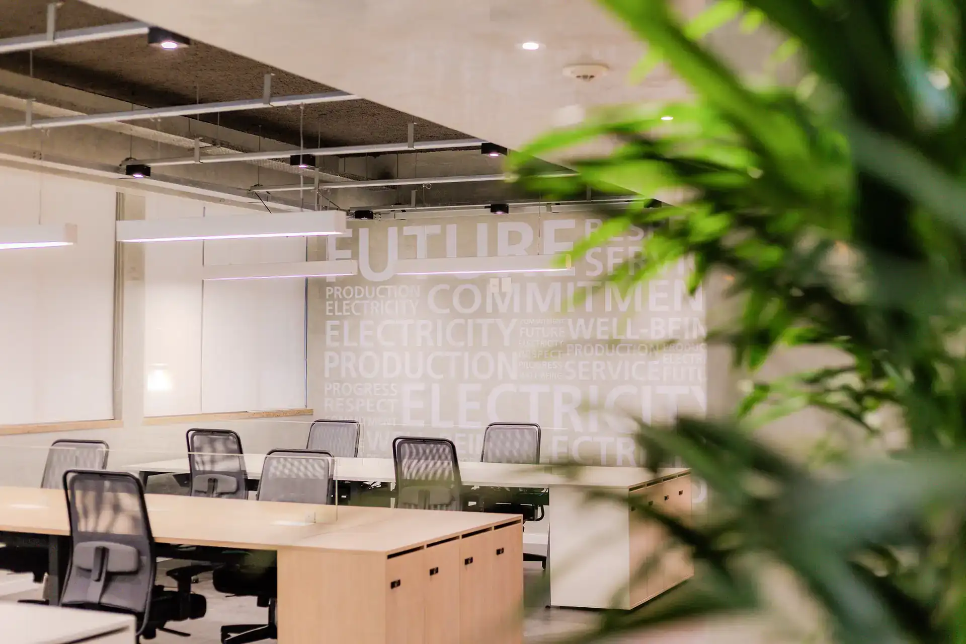 Área operacional da EDF Macaé com estações de trabalho, iluminação técnica e parede com palavras-chave. Obra corporativa focada em amplitude e eficiência.