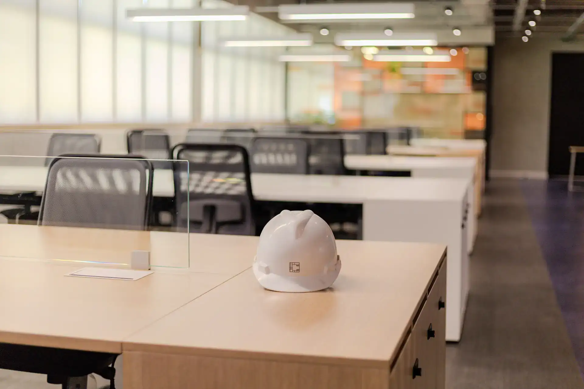 Capacete da Custódio Arquitetura posicionado sobre bancada no escritório da EDF em Macaé, simbolizando supervisão técnica e rigor na execução da obra corporativa.