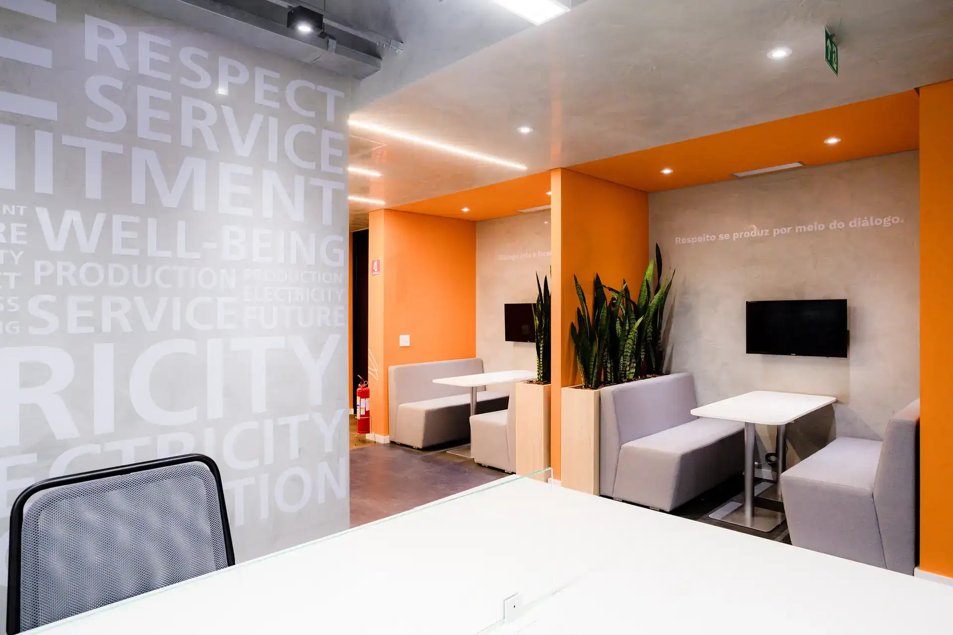 Ambiente integrado com booths, mesas de apoio e parede com tipografia. Escritório reformado pela Custódio Arquitetura com layout que favorece convivência e produtividade.