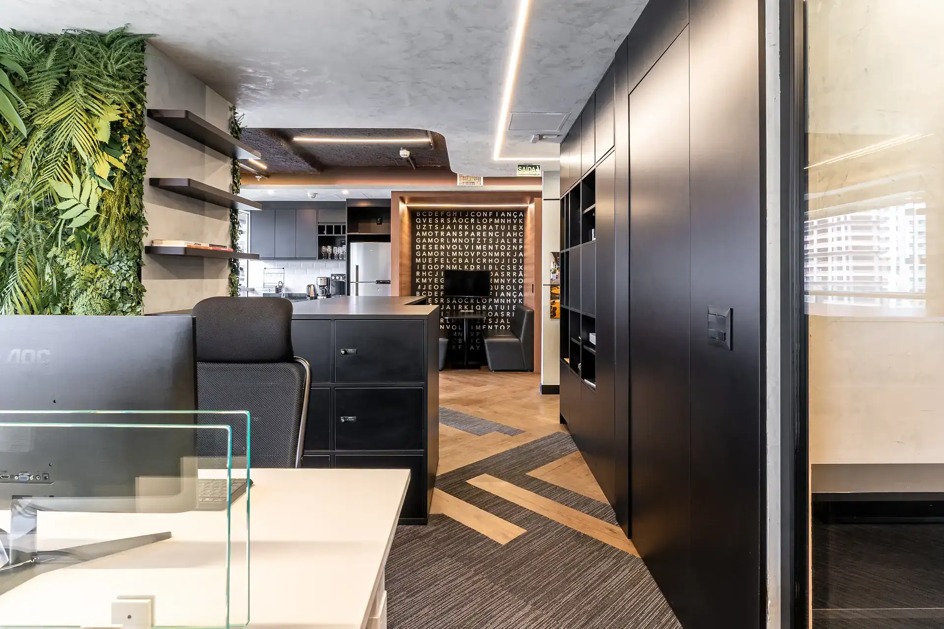 Open space com estações de trabalho e circulação fluida, integrando iluminação técnica e acabamentos elegantes em ambiente de obra corporativa concluída.