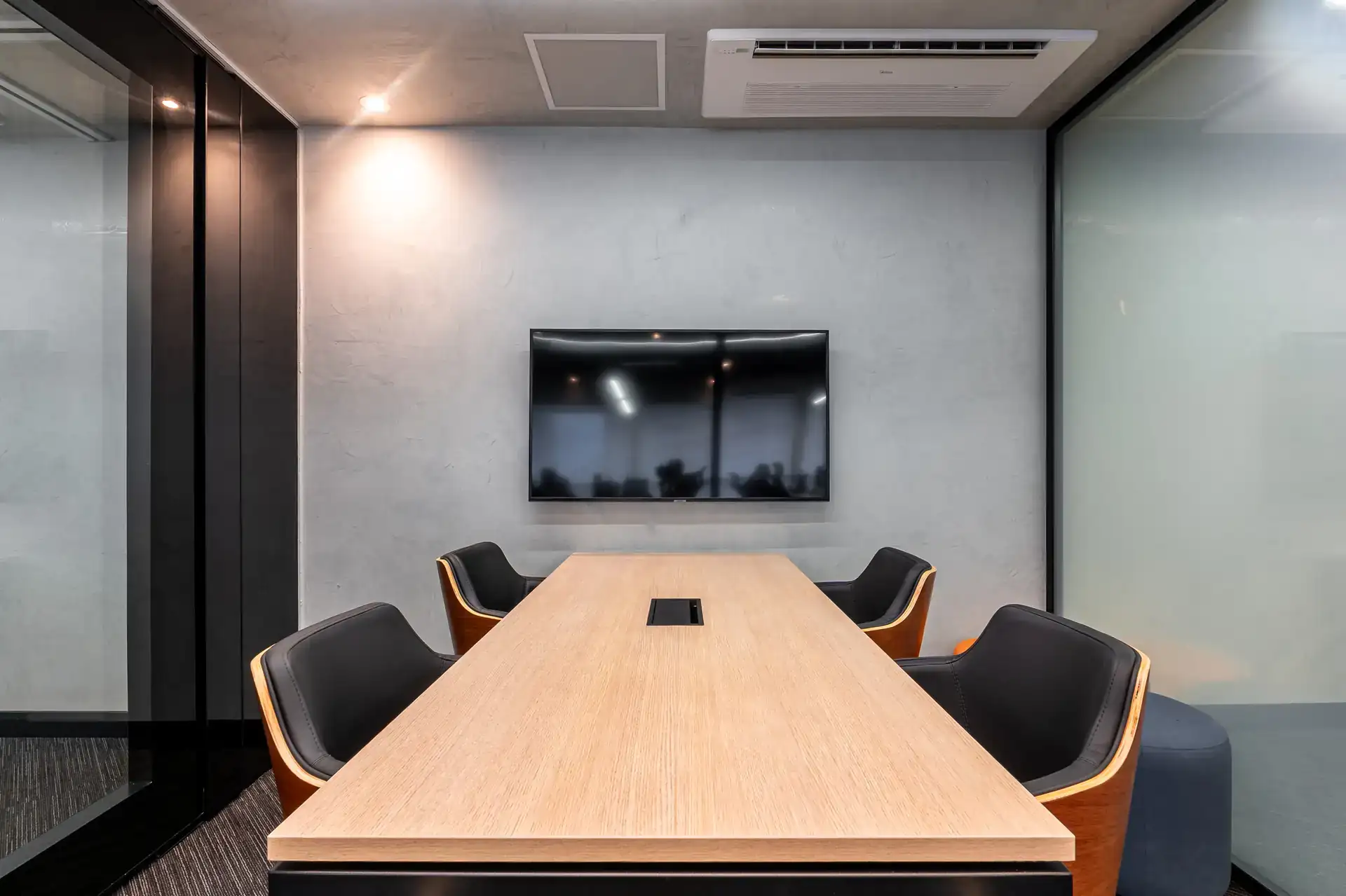 Sala de reunião maior, com mesa ampla, TVs e forro acústico, ambiente pensado para reuniões estratégicas dentro de uma obra corporativa premium.