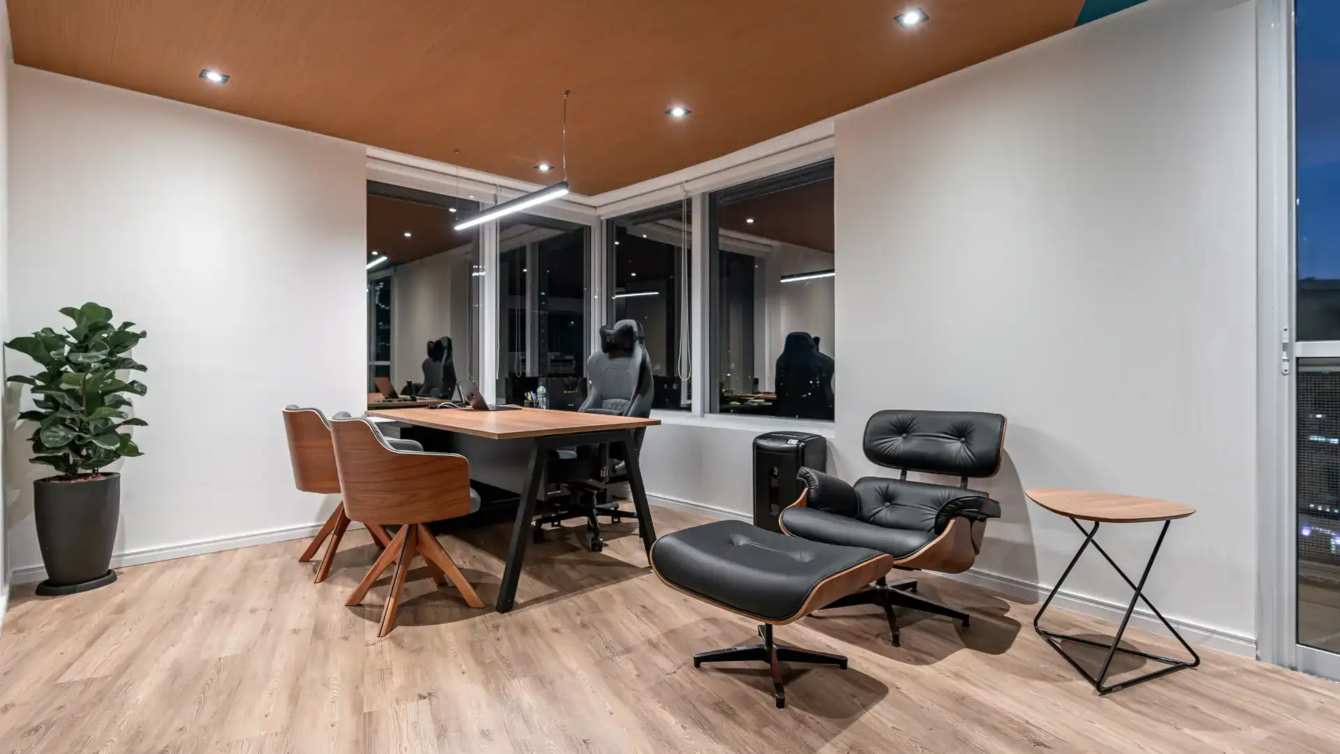 Sala de diretoria com mesa de madeira e poltronas, projeto de arquitetura corporativa moderno e minimalista.