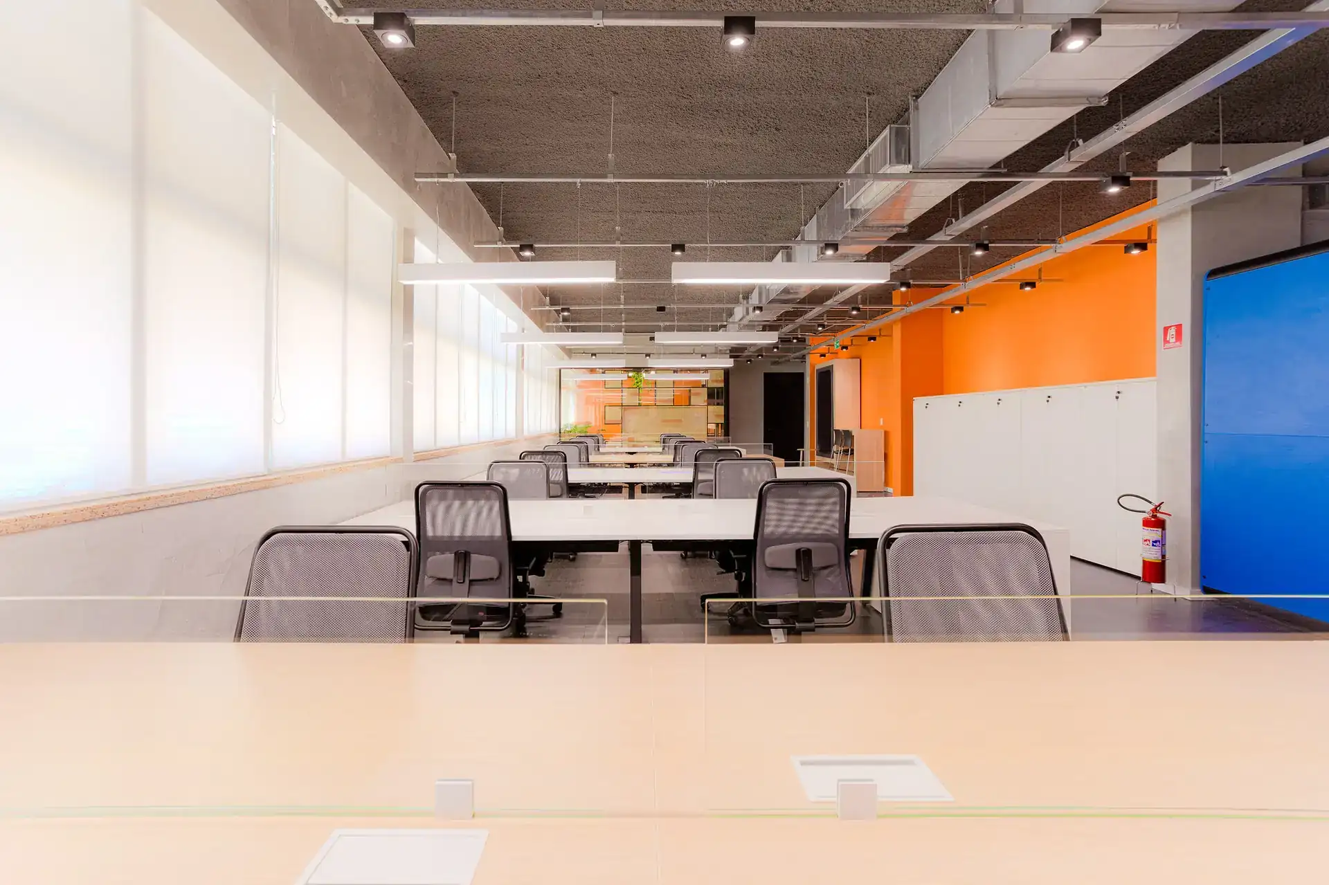 Open space do escritorio da EDF em Macaé desenvolvido em projeto de arquitetura corporativa, com estações alinhadas, iluminação linear e paleta vibrante, após reforma corporativa.