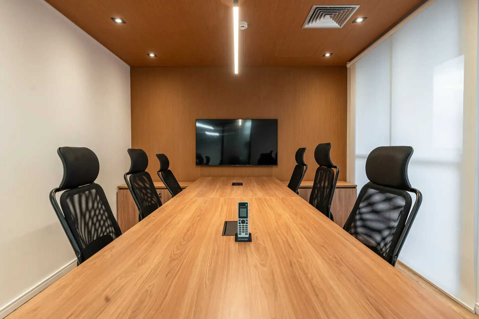 Sala executiva com mesa ampla e painel de madeira ao fundo, representando a reforma corporativa do escritório da MHM com foco em funcionalidade e estética.