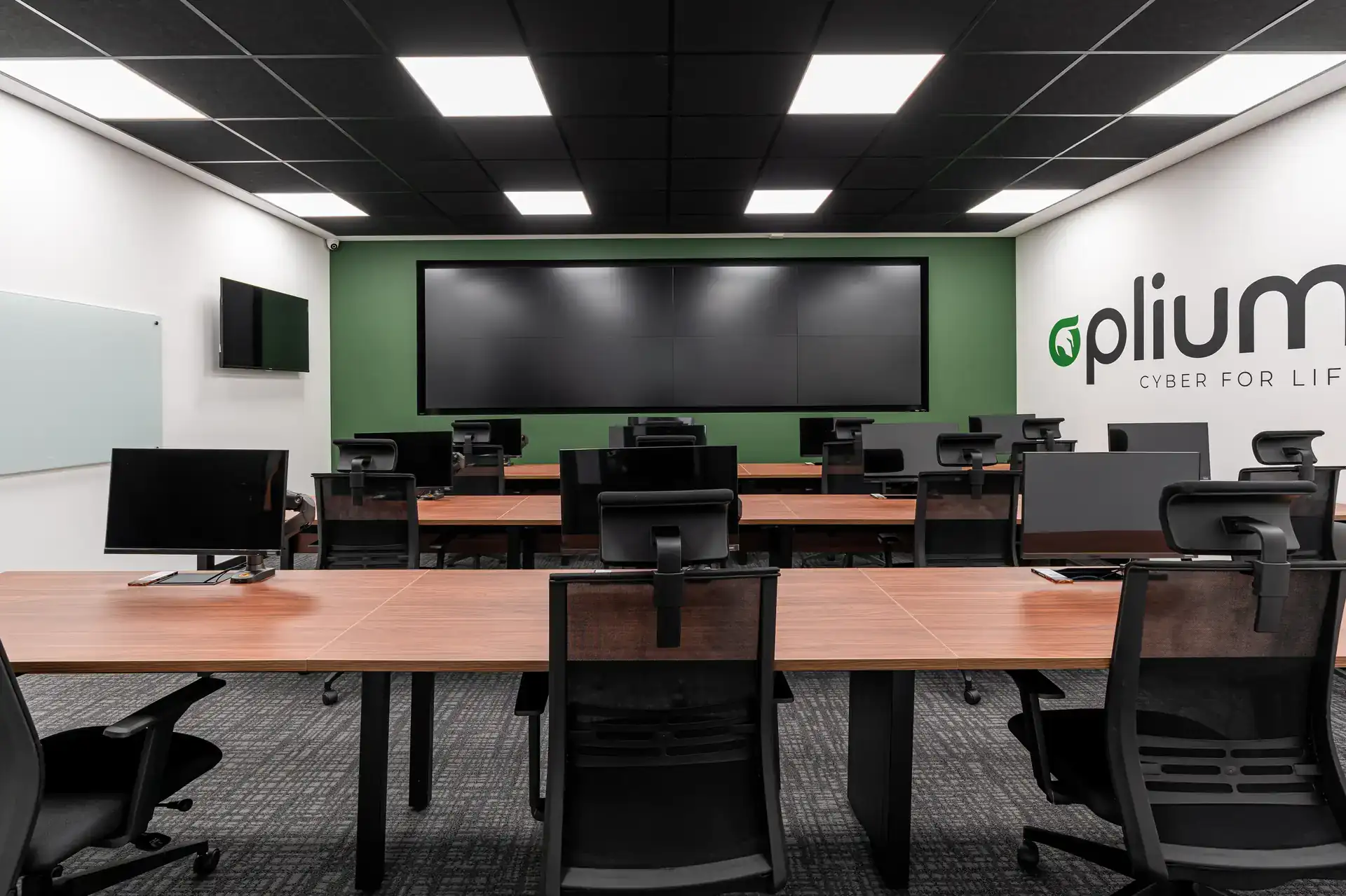 Ambiente de operações do escritório da Oplium com mesas amplas, cadeiras ergonômicas e videowall, planejado em projeto de arquitetura para alto desempenho corporativo.