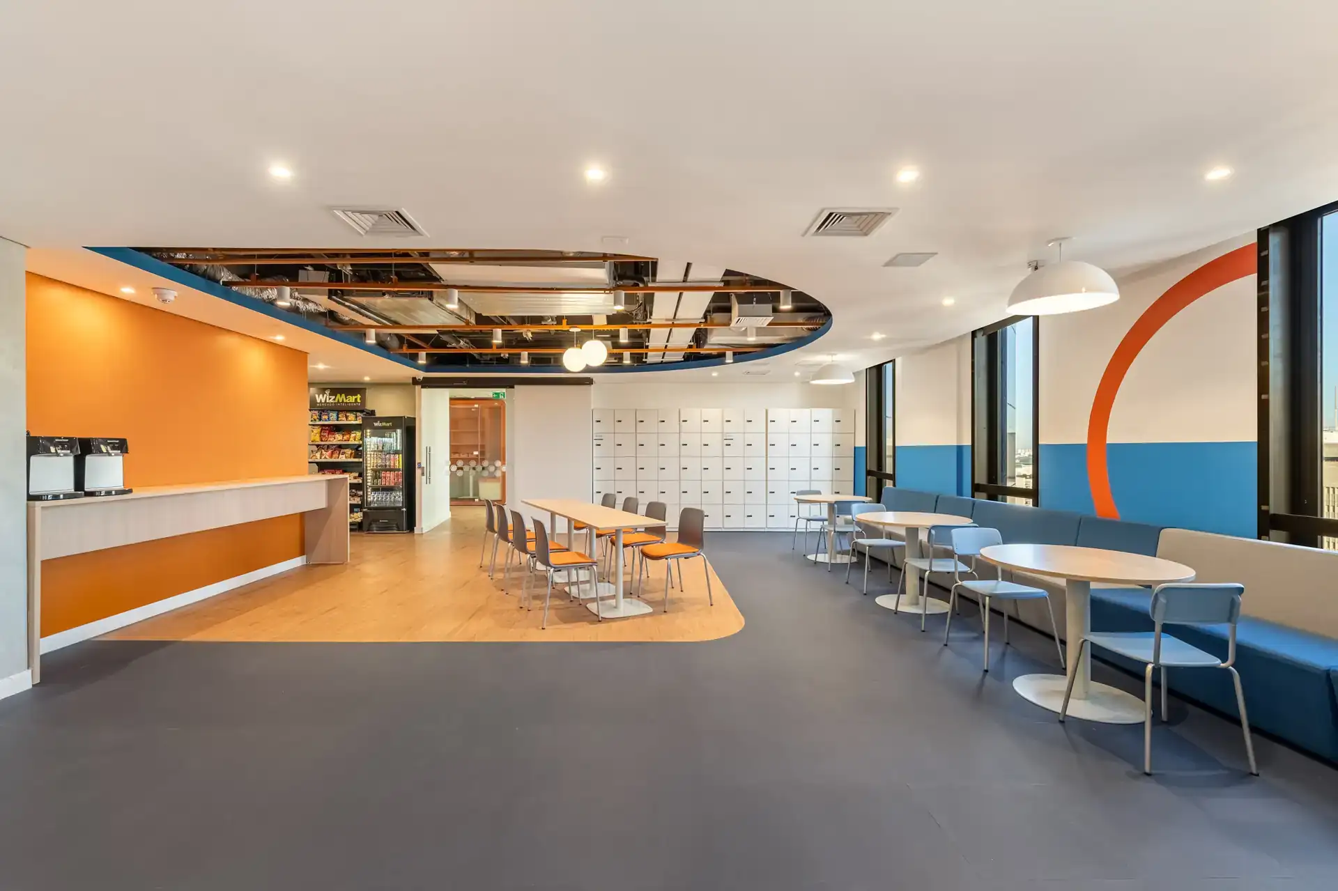 Ambiente de pausa com mesas e long bench, criado em reforma corporativa no escritório da Recovery, pelo escritório de arquitetura corporativa Custódio, para oferecer conforto e interação entre colaboradores.