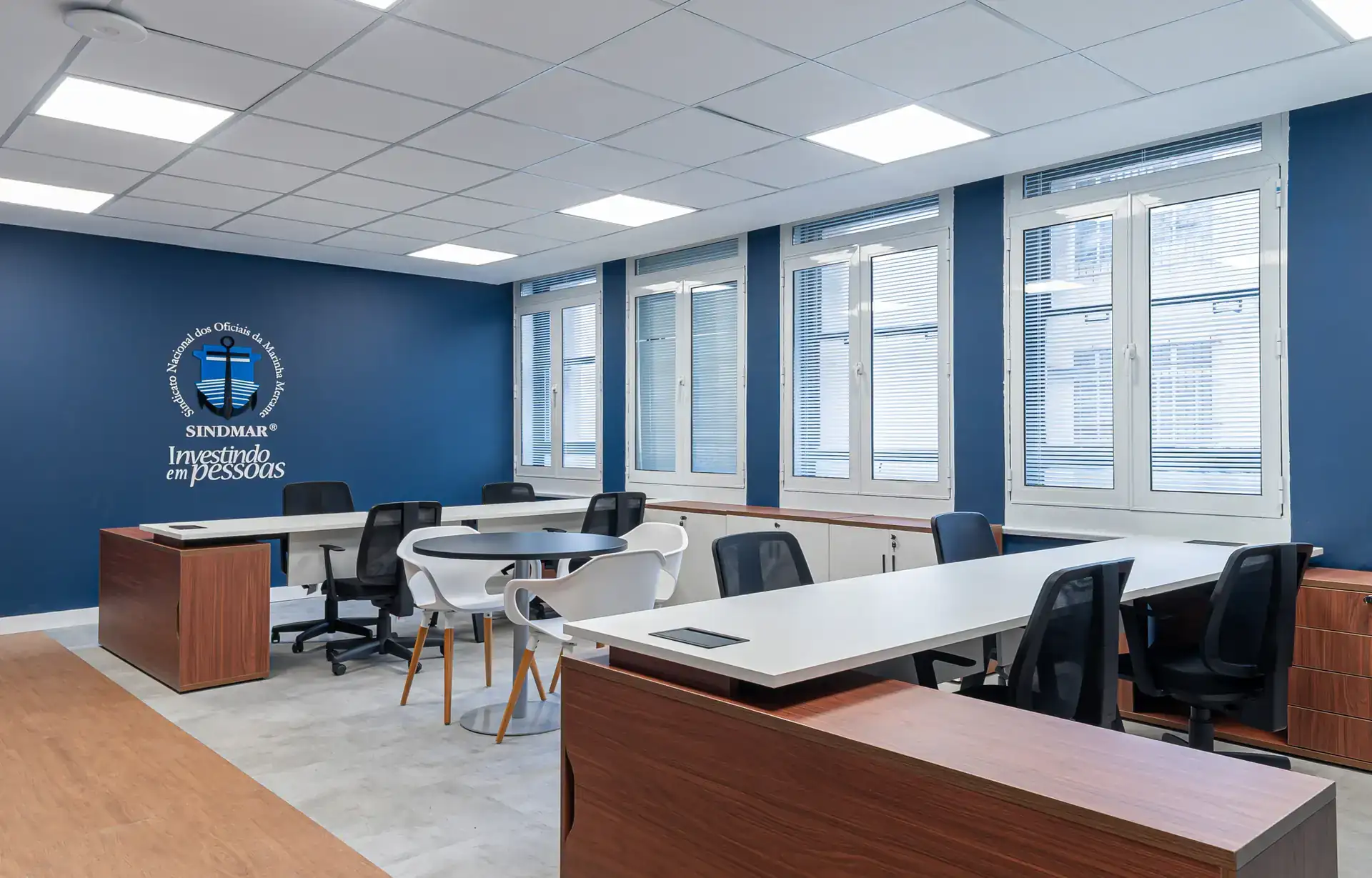 Sala corporativa ampla do escritório do SINDMAR com mesas de trabalho e área de reunião integrada, mostrando projeto de arquitetura voltado à funcionalidade no ambiente de escritório.