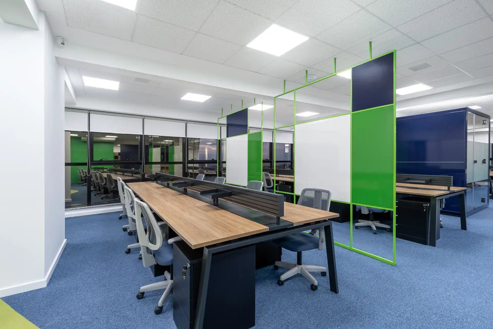 Open space com estações de trabalho, divisórias verdes e grande circulação, destacando solução de projeto de arquitetura aplicada na reforma corporativa do escritório da Transit BR.