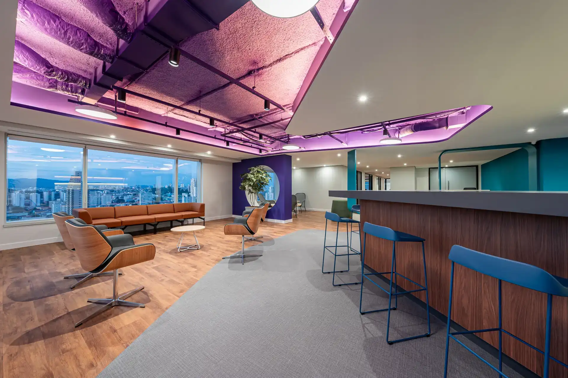 Espaço integrado do escritório da Inove com mobiliário colorido, iluminação moderna e vista panorâmica. Projeto de arquitetura e obra corporativa finalizados.