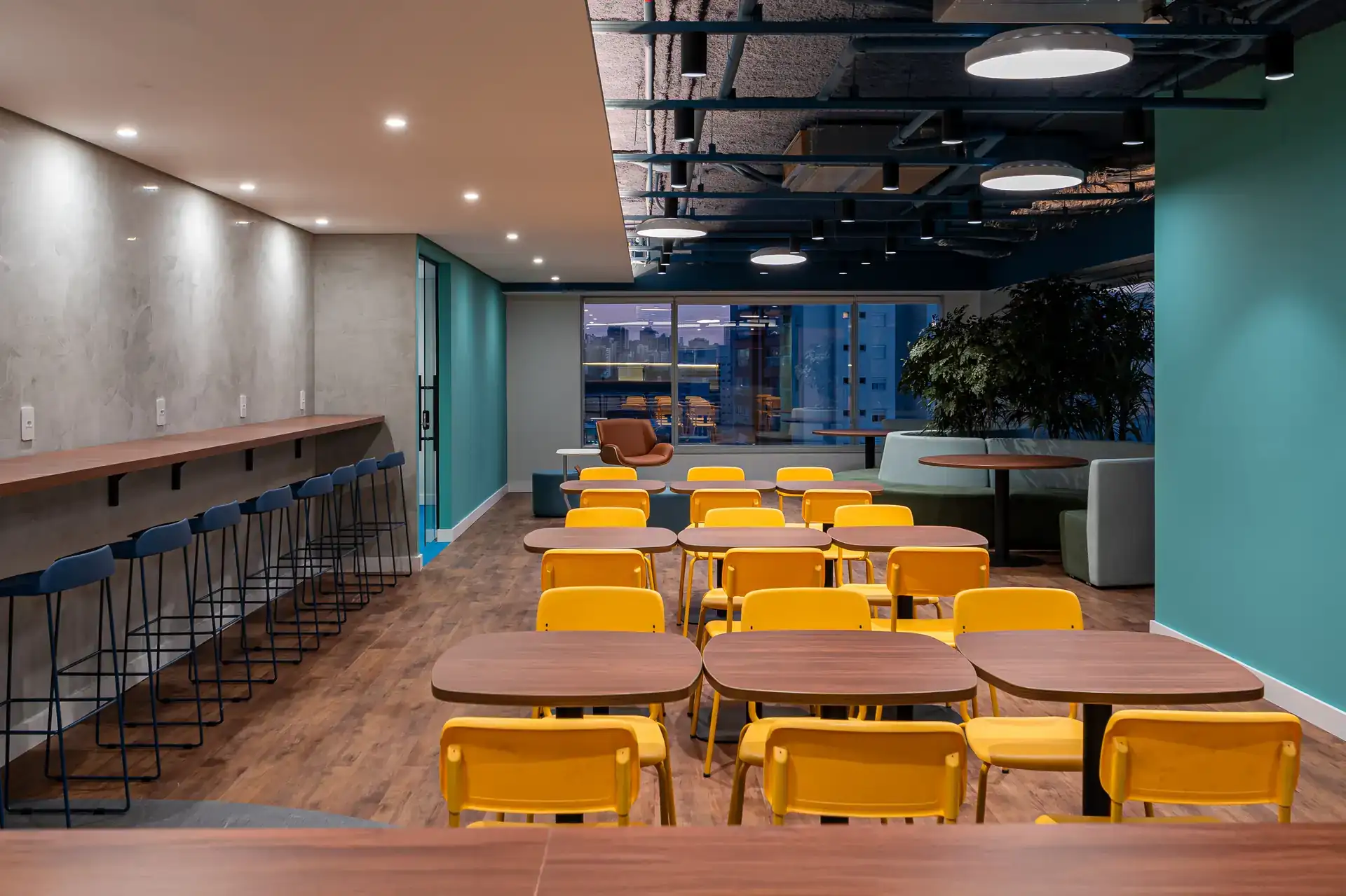 Refeitório corporativo finalizado do escritório da Inove com cadeiras amarelas, mesas de madeira e ambiente moderno. Projeto de arquitetura corporativa entregue.