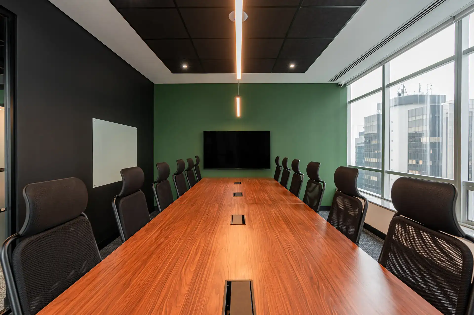 Boardroom do escritório da Oplium com mesa em madeira, iluminação pendente e vista urbana, solução de projeto de arquitetura para reuniões estratégicas.