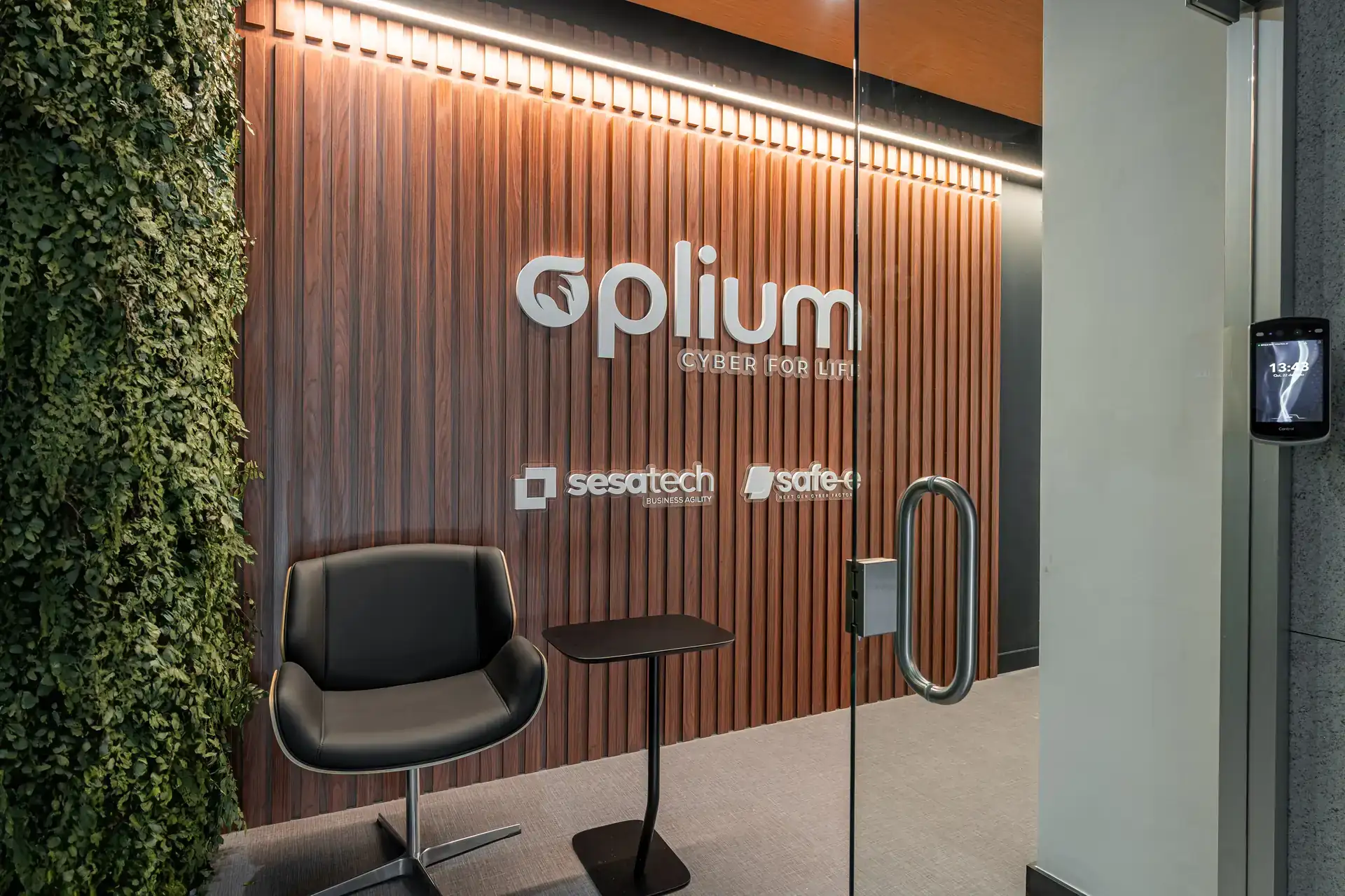 Recepção da Oplium com painel ripado de madeira, poltrona moderna e jardim vertical, representando solução de projeto de arquitetura para ambientes corporativos.