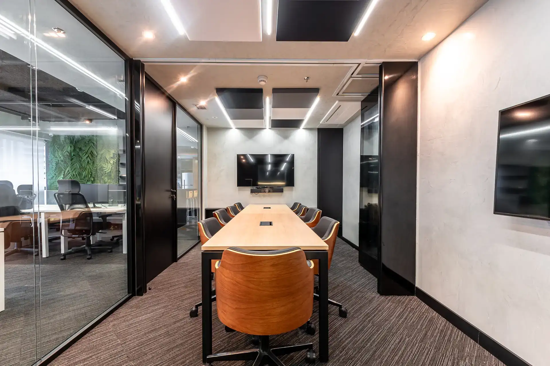 Sala de reunião moderna do escritório da Custódio com mesa central, cadeiras em madeira e iluminação técnica. Destaque para o projeto de arquitetura corporativa sofisticado.