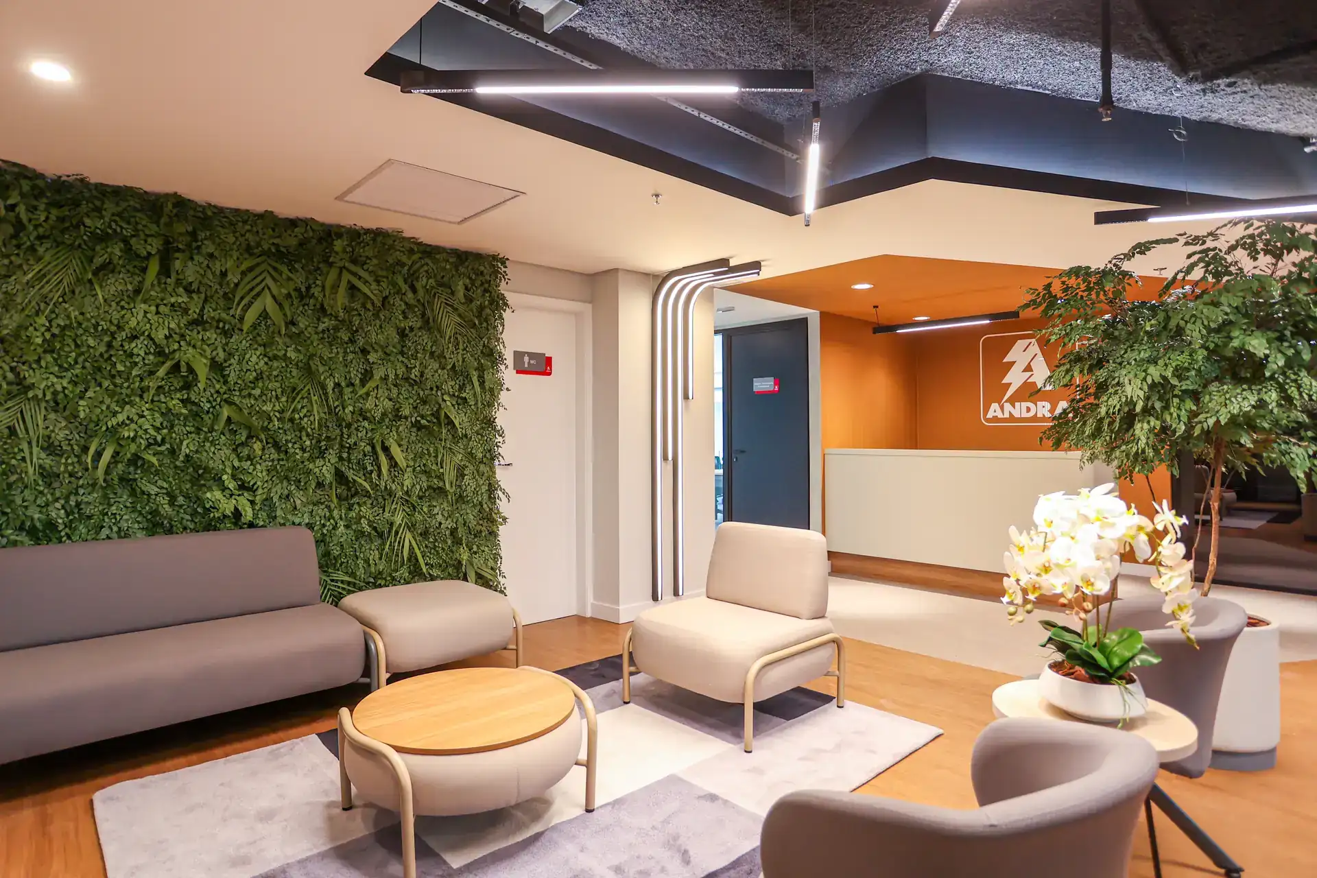 Recepção da Andra com parede verde, mobiliário moderno e iluminação linear, representando projeto de arquitetura e reforma de escritório concluída em obra corporativa.