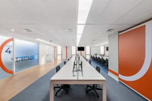 Open space corporativo do escritório da Recovery, com longas bancadas e divisórias de vidro, resultado de reforma de escritório voltada para grandes equipes.