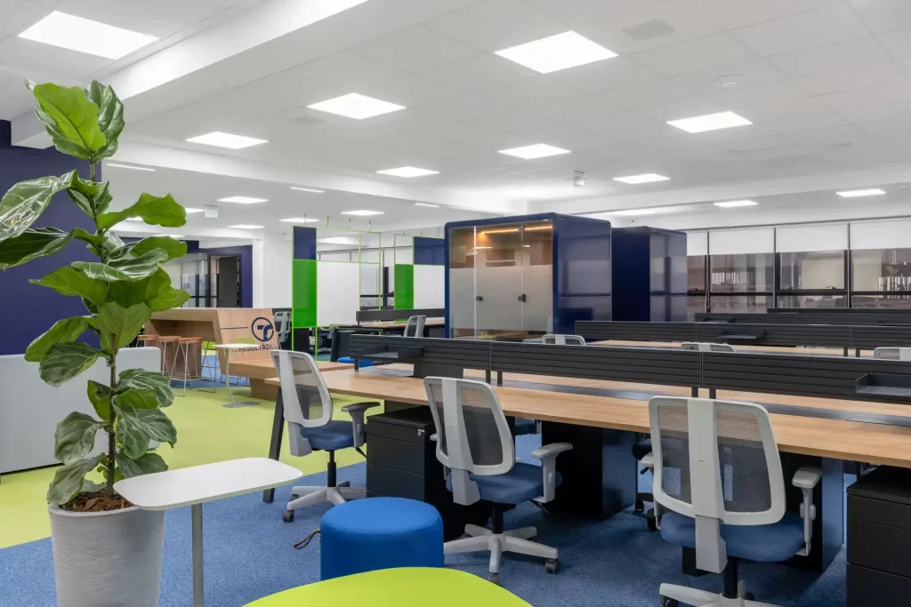 Open space corporativo com estações de trabalho, phone booth envidraçada e áreas colaborativas, destacando soluções de projeto de arquitetura e reforma de escritório da Transit BR.