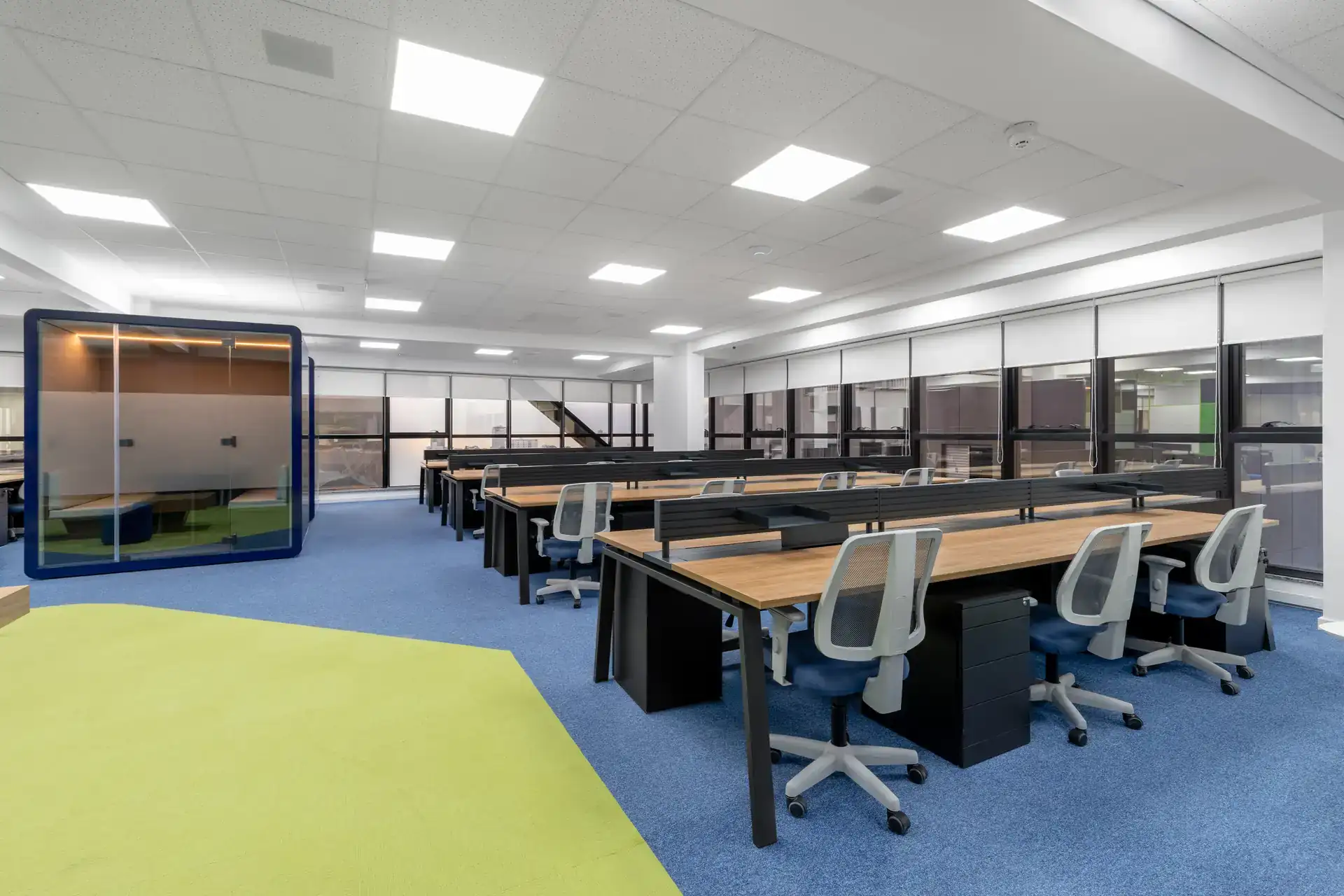 Estação de trabalho corporativa ampla com mesas contínuas e cadeiras ergonômicas, parte de uma reforma de escritório e projeto de arquitetura para a Transit BR voltada para produtividade e conforto.