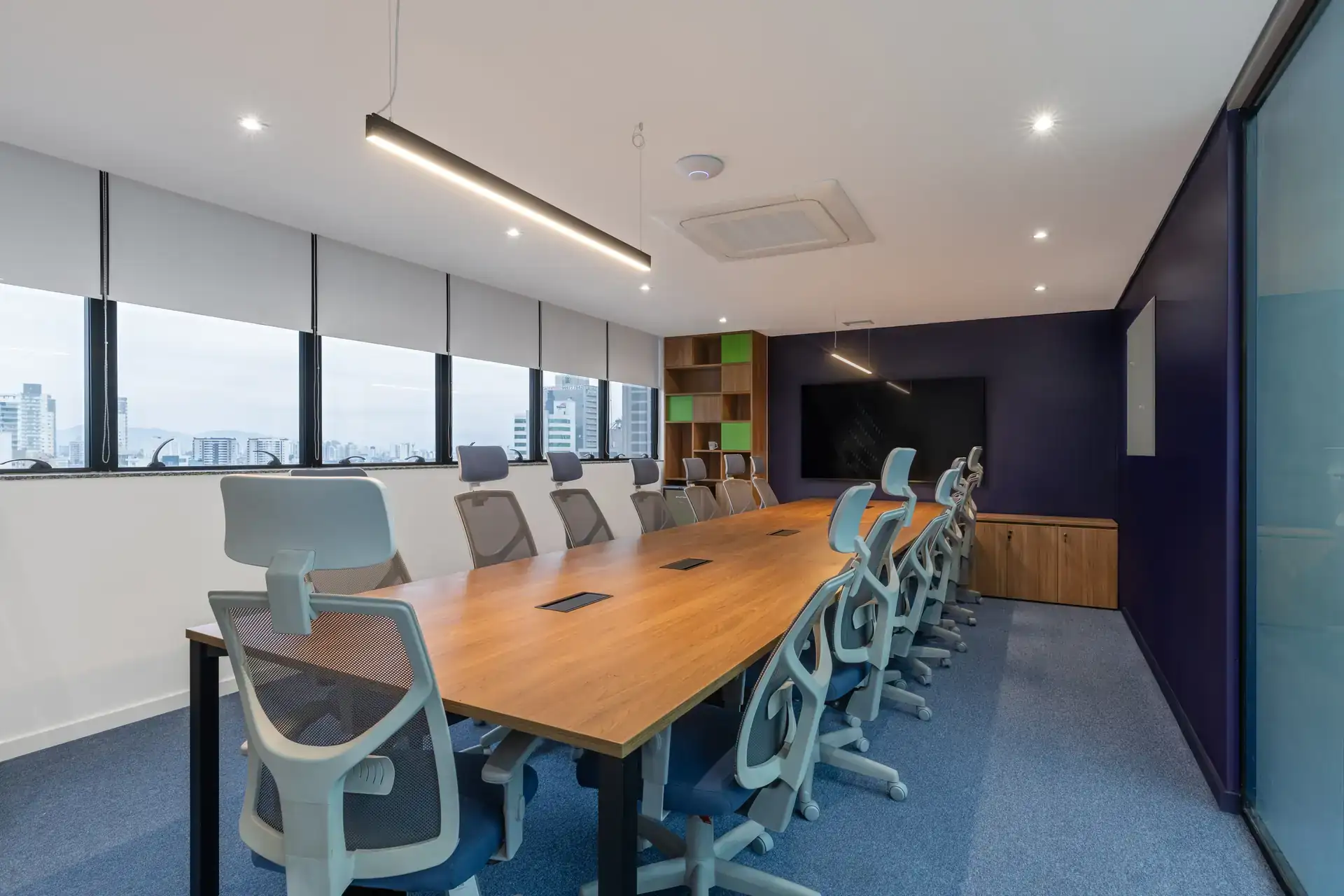 Sala de reunião ampla em escritório corporativo, com mesa grande e cadeiras ergonômicas, resultado de um projeto de arquitetura moderno voltado para ambientes de trabalho e reformas corporativas eficientes.
